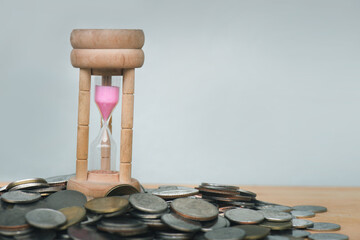 The hourglass is in the middle of a pile of silver coins piled on a wooden floor. The picture shows...