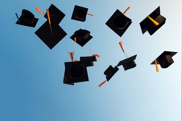 Graduates throw black hats in the sky.