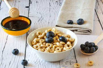 Honey rings with blueberries in a bowl on the table wooden background. Copy space. Top view. Flat lay. Horizontal orientation.