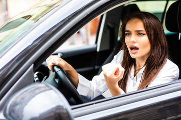 Angry young woman driver threatens other drivers with a fist. Traffic jams concept.