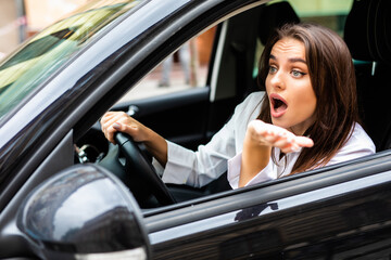 Beautiful angry woman honking in her car while driving on the street