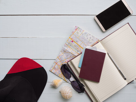 Accessories summer travel sea concept. passport, cap, mobile, book. glasses, sea shell, blur image of map on wood background.