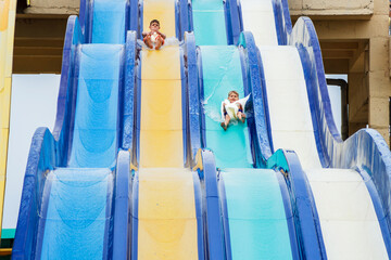 Two brothers are swiftly descending the slide in the water park. Family vacation at the water park....