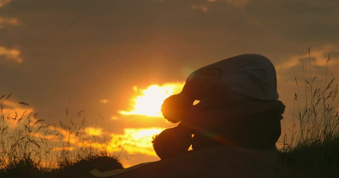 Two people doing yoga at sunset. A time lapse of the large orange sunset as the massive sun sets into the horizon. Sunset sky clouds. Sunset sky background. Sunset sky orange.