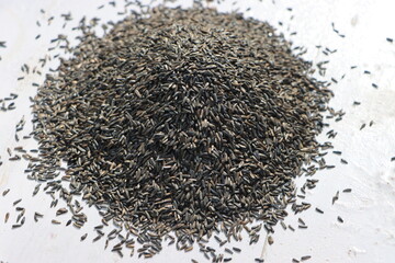 Black Niger seeds, Guizotia abyssinica heaped on white wooden table