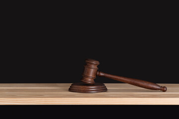 Wooden judge gavel on wooden table, black background. Wood hammer auction