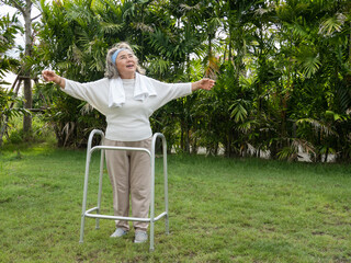 Smile happy elderly Asian woman use walker with strong health while walking in the garden