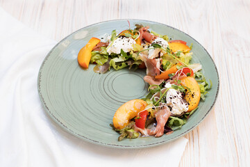 Salad with ham and peach on a large round dish, delicious summer salad in the restaurant