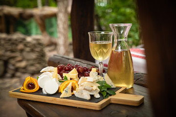 Carafe with white wine on a wooden table. With a glass and a bunch of grapes
