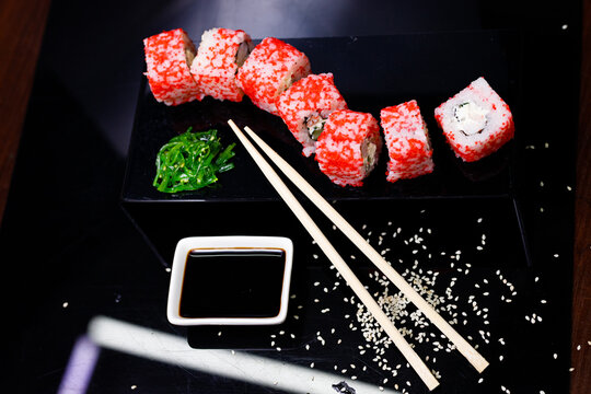 Sushi with salmon. Soy sauce, red caviar. Sushi on a black background.