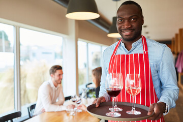 Waiter serving glasses with wine on a tray