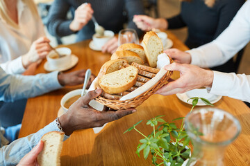 Hands distribute bread to soup at lunch