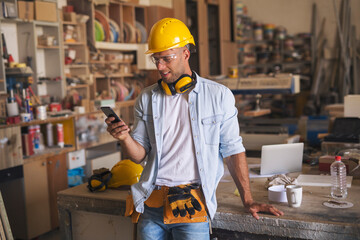 Portrait of a good looking carpenter using cell phone