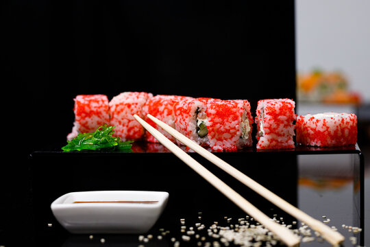 Sushi with salmon. Soy sauce, red caviar. Sushi on a black background.