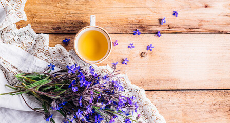 wooden background with a bouquet of blue flowers and a cup of tea. long banner