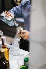 Detalle de manos de camarero sirviendo gintonic añadiendo ginebra en un dosificador
