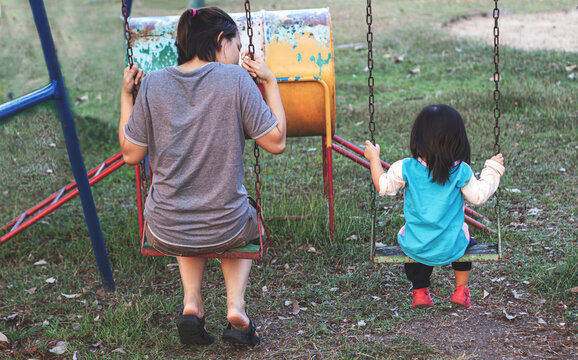 Mother And Kid Talking On Swing At Play Park