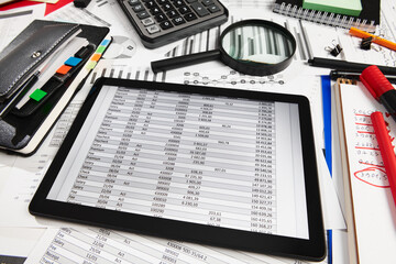 Top view of office employee's desk - work with tablet pc computer and financial reports, analysis and accounting, tables and graphs, various office items for bookkeeping