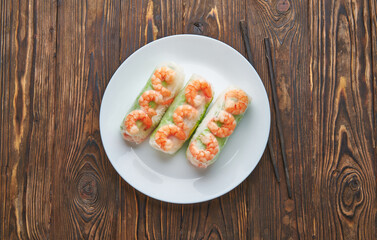 Asian food spring rolls with shrimps on a dark wooden background. Spring rolls in rice paper with a chopsticks. Top view space for text