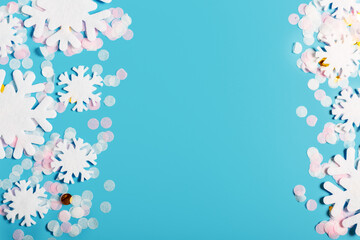 Obraz na płótnie Canvas White snowflakes and confetti on a blue background. Snow and winter concept. New year and christmas concept. Beautiful winter background. Top view, flat lay, copy space.