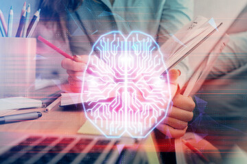 Double exposure of woman's writing hand on background with brain hud. Concept of learning.