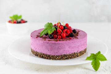 Raw cashew black currant cake on chocolate granola, garnished with fresh berries. Sugar, lactose, gluten free.