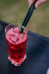 The bartender uses tweezers to add rosemary to the pink cocktail with ice. Summer party catering.