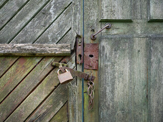Old forgotten wooden door and key lock with a padlock