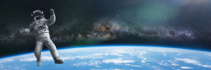 astronaut during a spacewalk in orbit of planet Earth, background banner with empty space  © dottedyeti