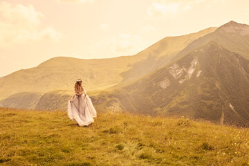 Fototapeta premium girl walks on the grass against the background of mountains.