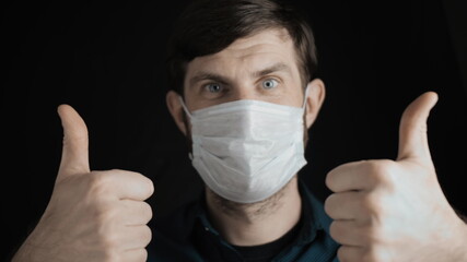 Attractive bearded man is putting on surgical mask on his face for corona virus covid-19 prevention. Infection protection, quarantine and epidemic concept. Slow motion close up front view 4k video.