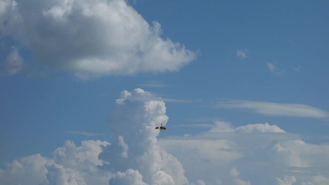 Flight of an ultralight helicopter in a blue sky with clouds