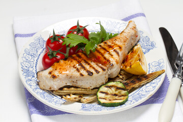 Grilled swordfish steak, young corn, zucchini, lemon, cherry tomatoes, chili sauce and celery leaf