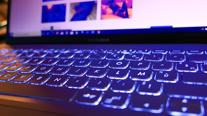 Close-up on a laptop keyboard. Erotic photos that appear on the screen in the background deliberately blurred.	