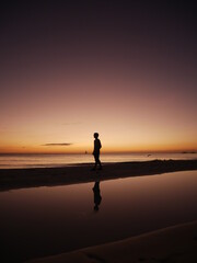 silhouette of a man walking on the beach at sunset