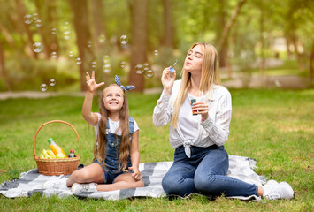 Mom And Daughter Blowing Soap Bubbles Having Picnic Outdoors