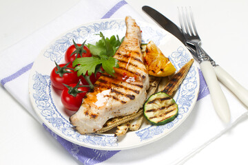 Grilled swordfish steak, young corn, zucchini, lemon, cherry tomatoes, chili sauce and celery leaf