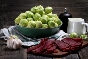 Raw Brussels sprouts, beef jerky, pepper and cream in rustic style