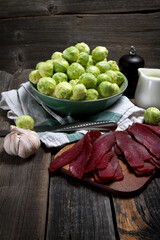 Raw Brussels sprouts, beef jerky, pepper and cream in rustic style