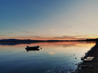 Obraz na płótnie Canvas Sunset on the lake. A pontoon on the lake surface during sunset. Otmuchow Poland.