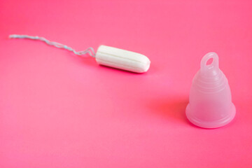 pink eco menstrual Cup and white tampon as methods of female hygiene during menstruation on a pink background