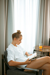 Pretty young teen girl in home clothes with a laptop working and drinking juice. Cozy home environment