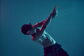 Fototapeta na wymiar Guy breakdancer in cap and sunglasses dance hip-hop in neon blue light. Dance school poster