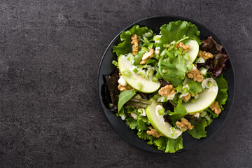 Fresh Waldorf salad with lettuce, green apples, walnuts and celery on black stone. Top view.Copy space	