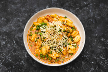 plant-based food, vegan potato gnocchi with sundried tomatoes and peas in red pesto sauce with dairy-free cheese