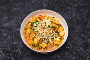 plant-based food, vegan potato gnocchi with sundried tomatoes and peas in red pesto sauce with dairy-free cheese