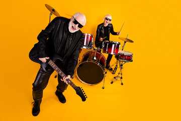 Portrait of nice attractive excited cheerful cheery grey-haired couple famous musicians performing rehearsal having fun garage isolated over bright vivid shine vibrant yellow color background