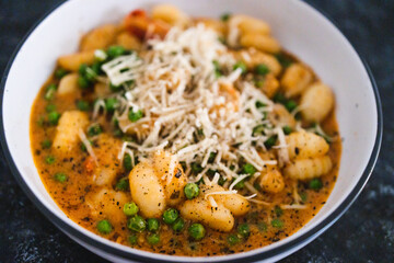 plant-based food, vegan potato gnocchi with sundried tomatoes and peas in red pesto sauce with dairy-free cheese