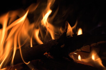 Burning wood at night. Campfire at touristic camp at nature in mountains. Flame amd fire sparks on dark abstract background. Cooking barbecue outdoor. Hellish fire element. Fuel, power and energy