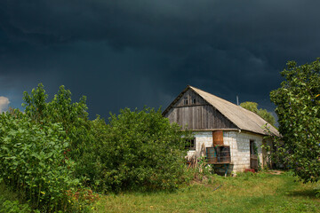 Fototapeta premium Heavy rain near an old abandoned house in a distant village. Green nature